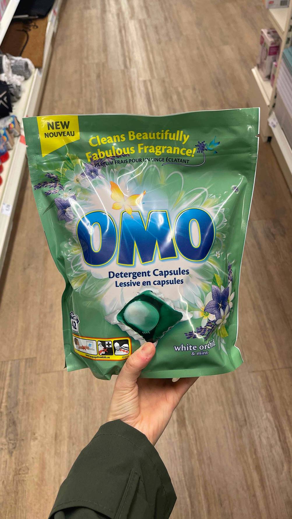 Das getestete Omo-Waschmittel in einer grünen Verpackung wird in der Hand gehalten.