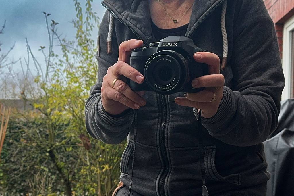 Die getestete Reisezoom-Kamera wird in der Hand zum fotografieren gehalten.