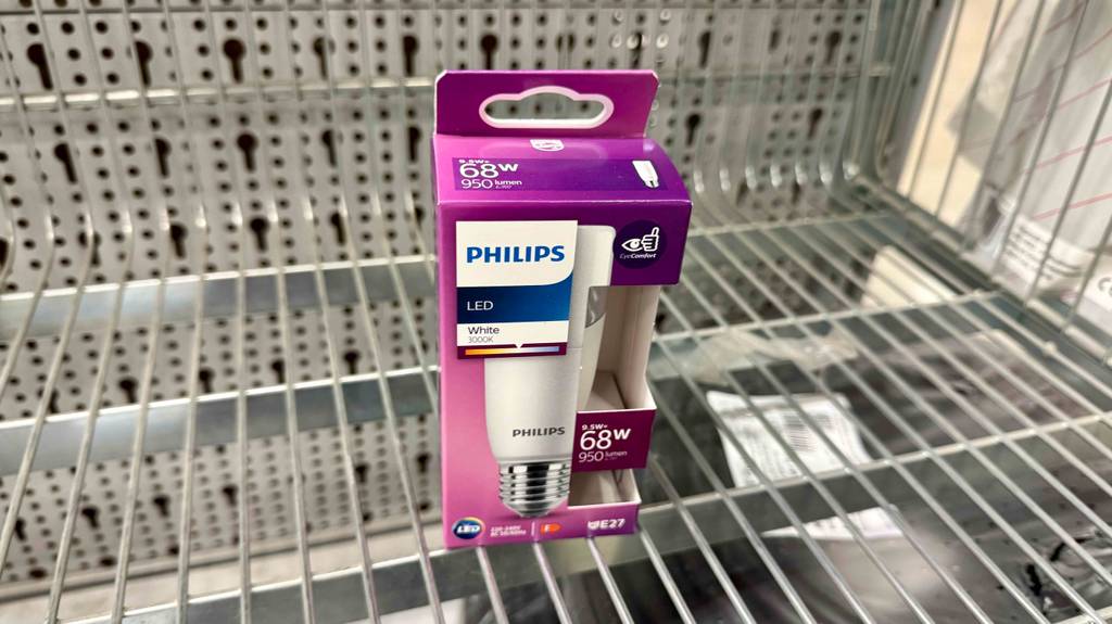 Ein pinke Verpackung mit einer getesteten dimmbaren E27-LED-Leuchte steht auf einem Regalgitterboden.