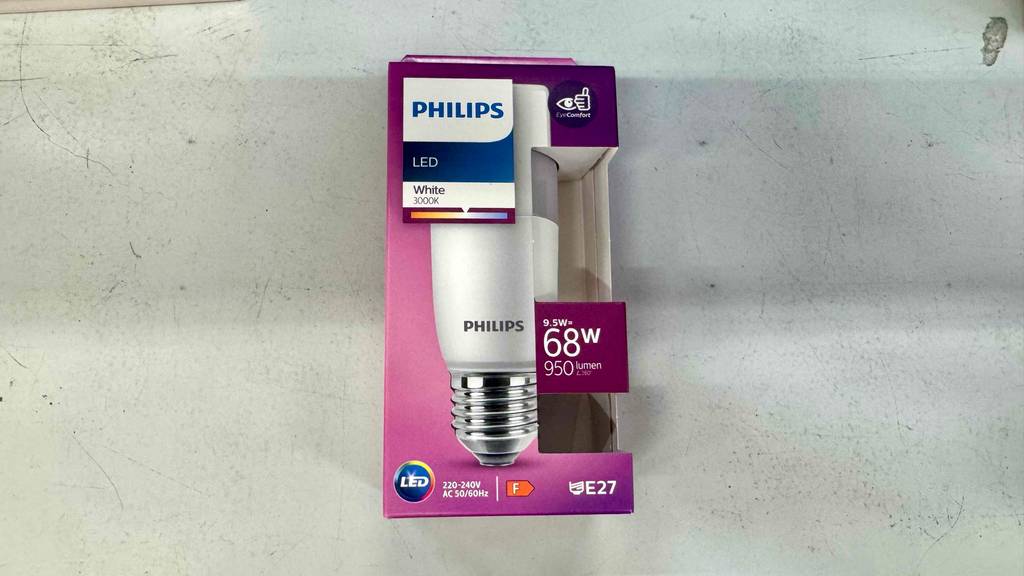Ein pinke Verpackung mit einer getesteten dimmbaren E27-LED-Leuchte liegt auf dem Boden.