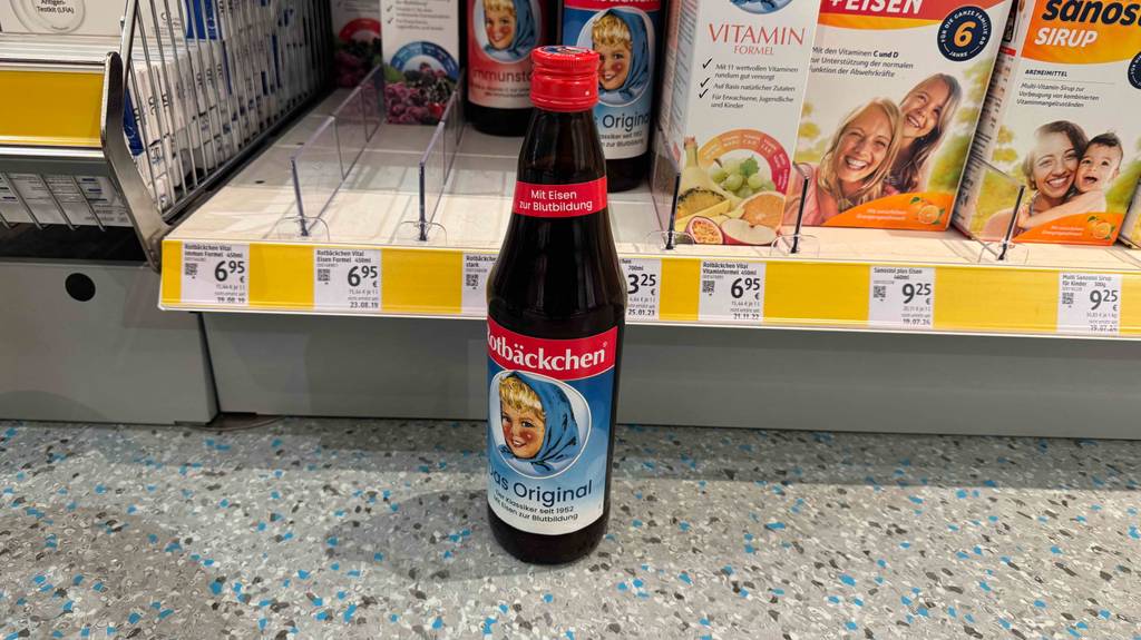 Der getestete Rotbäckchen-Saft steht vor einem Regal.