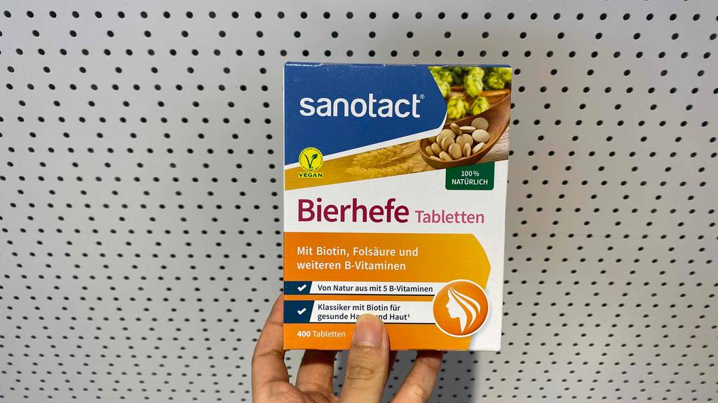 Bierhefe-Tabletten im Test: eine Packung Bierhefe-Tabletten der Marke Sanotact wird in der Hand gehalten - darauf Informationen zu enthaltenen Vitaminen abgebildet.