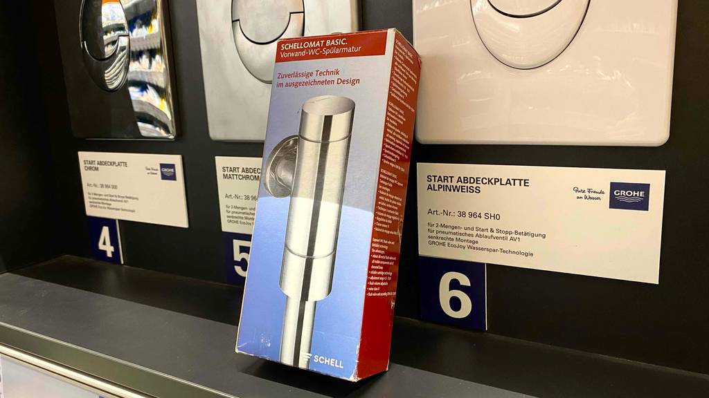 WC-Druckspüler-Test: Die Verpackung eines WC-Druckspülers ist neben Ausstellungsstücken in einem Geschäft angelehnt.