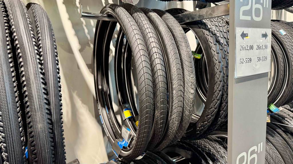 Fahrradreifen 26 Zoll-Test: Mehrere schwarze Reifen hängen nebeneinander an einem Verkaufsstand.