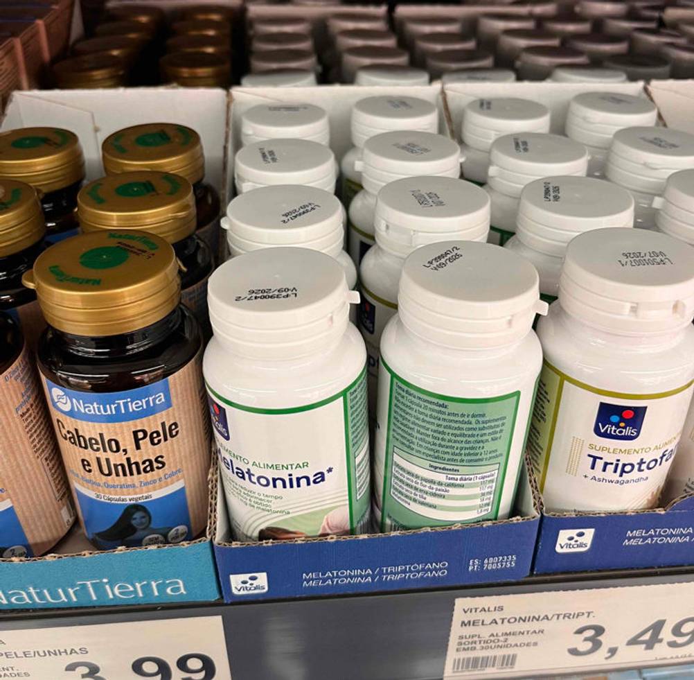 Melatonin im Test: mehrere Dosen Melatonin-Kapseln in einem Regal stehend neben anderen Produkten.