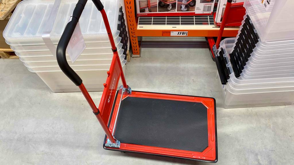 Ein getesteter Plattformwagen von schräg oben neben anderen Produkten auf einem grauen Boden.
