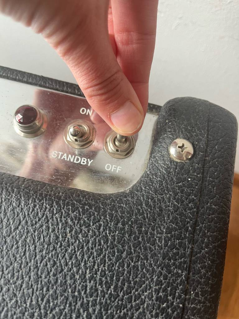 Ein- und Ausschalter des Akustikgitarren-Verstärkers, die gerade betätigt werden.