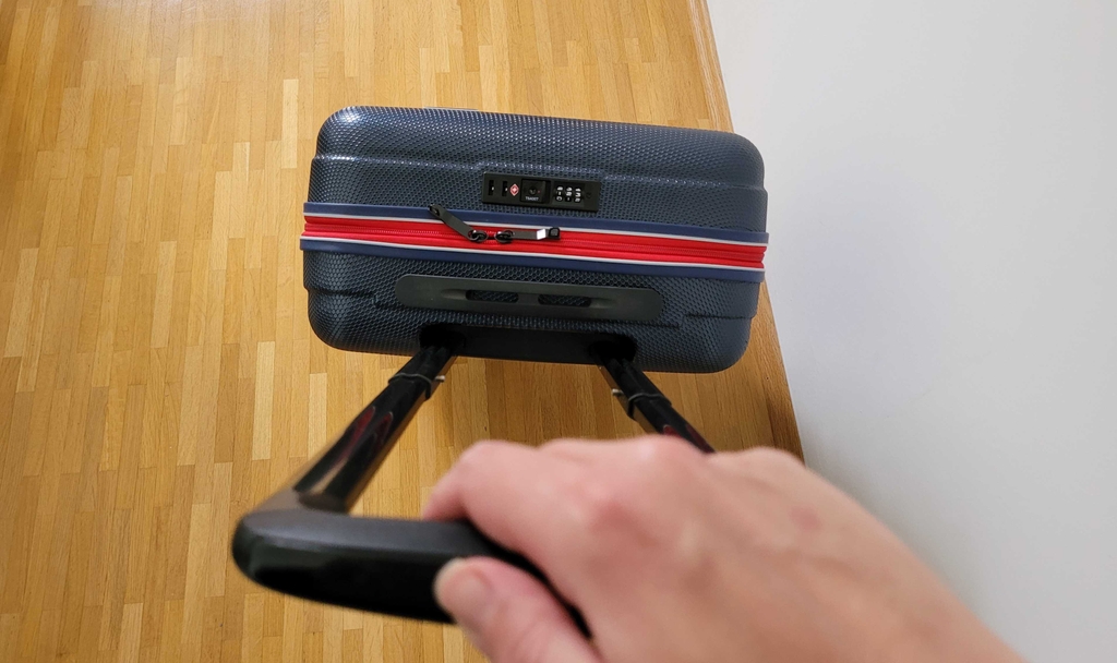 Geschlossener Koffer im Test wird an Teleskopstange gehalten.