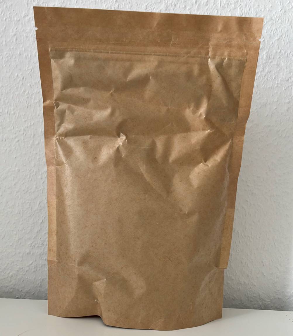 Moringa-Pulver-Test: Rückseite von Papierverpackung eines Moringa-Pulvers stehend auf einer weißen Fläche.