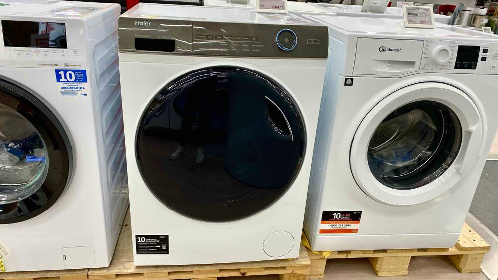 Haier-Waschmaschine im Test: eine Haier-Waschmaschine mit verschlossener Türe steht neben anderen Modellen in einem Geschäft.