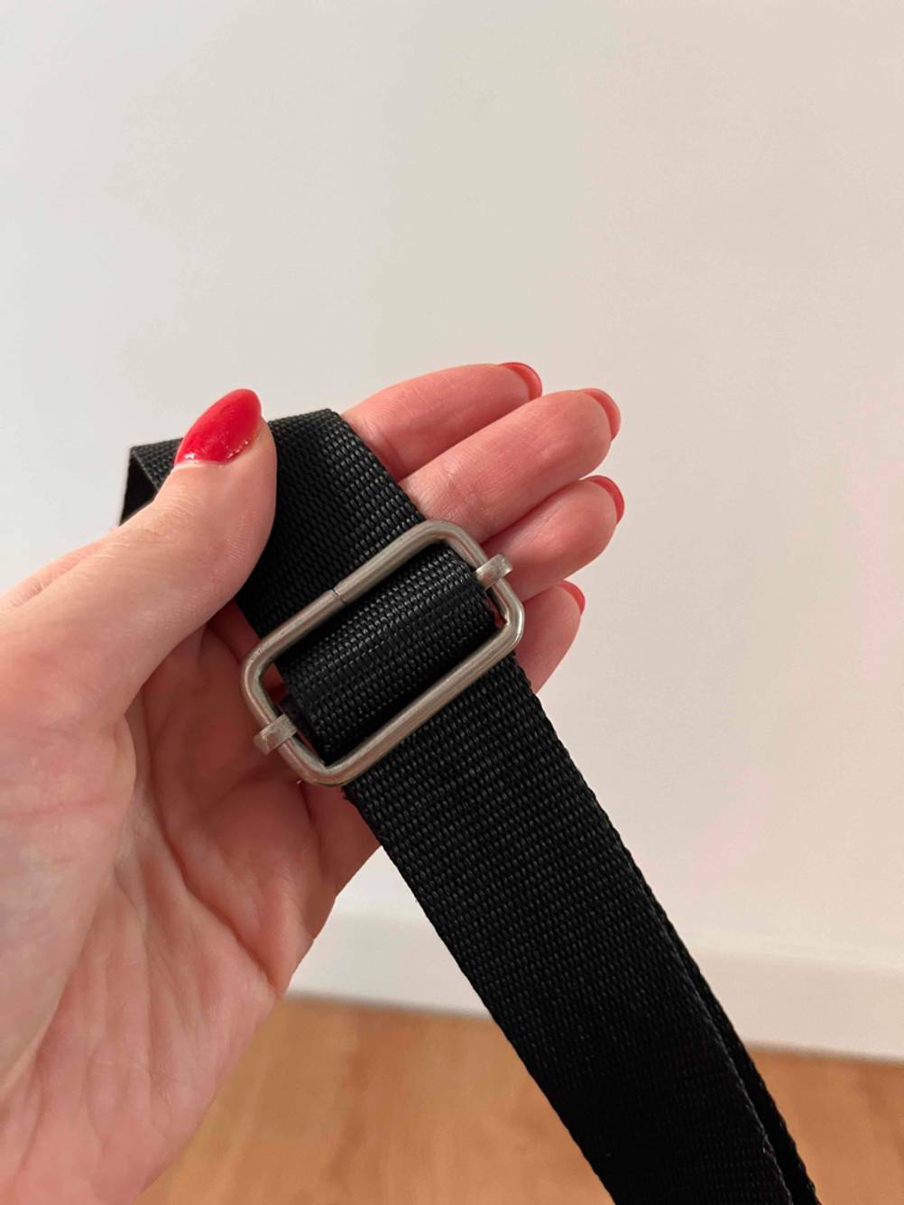 Weekender getestet: Eine Hand hält einen Trageriehmen vor eine helle Wand