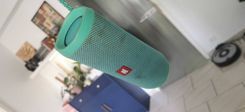 Bluetooth Lautsprecher wird an der Schnur in der Luft gehalten.