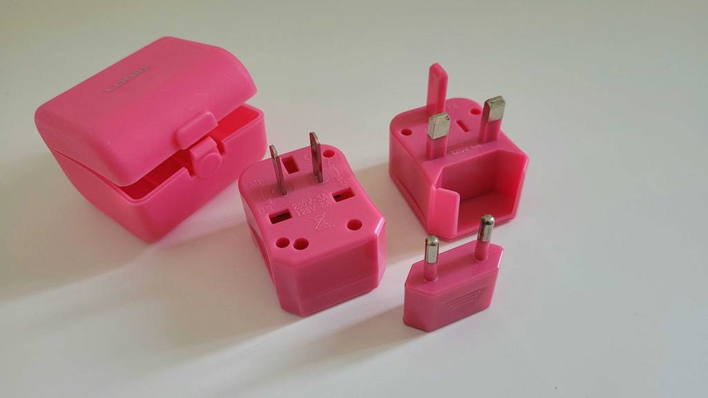 Steckdosenadapter getestet: mehrere Teile eines Steckdosenadapters auf einer weißen Fläche liegend.