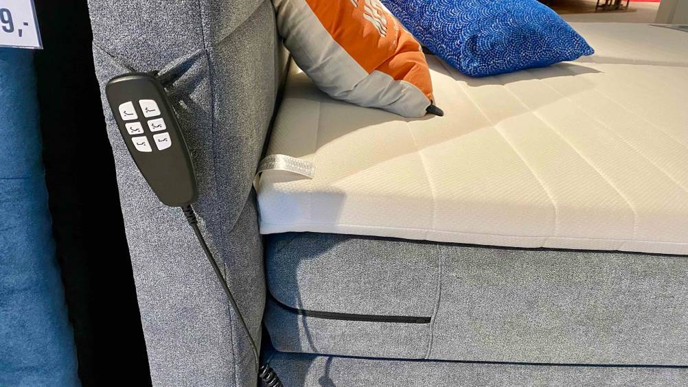 Boxspringbett-elektrisch-Test: Eine Fernbedienung ist seitlich am Kopfteil eines Polsterbettes befestigt.