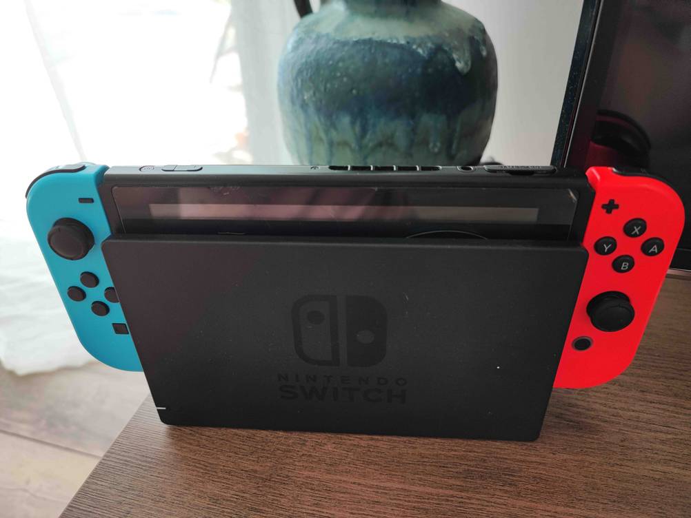 Handheld-Konsole-Test: Nintendo Switch steht in Ladestation auf einem Holztisch im Wohnzimmer. 