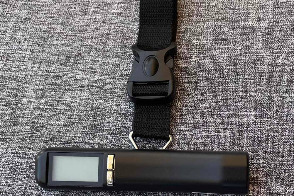 Kofferwaage im Test: liegende, schwarze, digitale Kofferwaage mit Haltegurt.