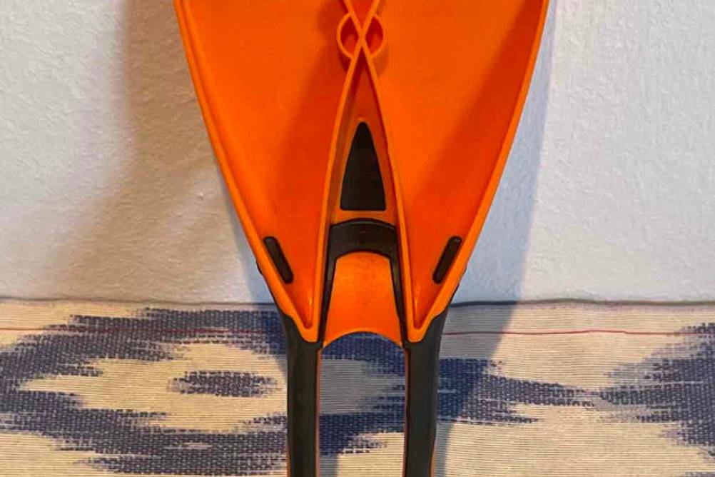 Rückseite eines an der Wand lehnenden, getesteten Eiskratzers in Orange mit schwarz gummiertem Griff.