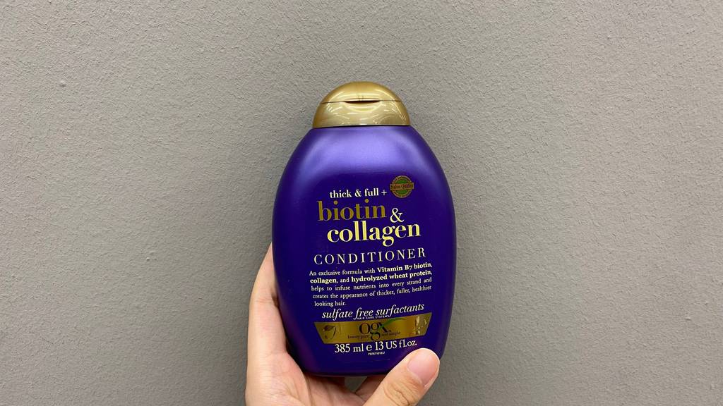 OGX-Shampoo im Test: Eine Hand hält eine Flasche Shampoo vor einer hellen Oberfläche