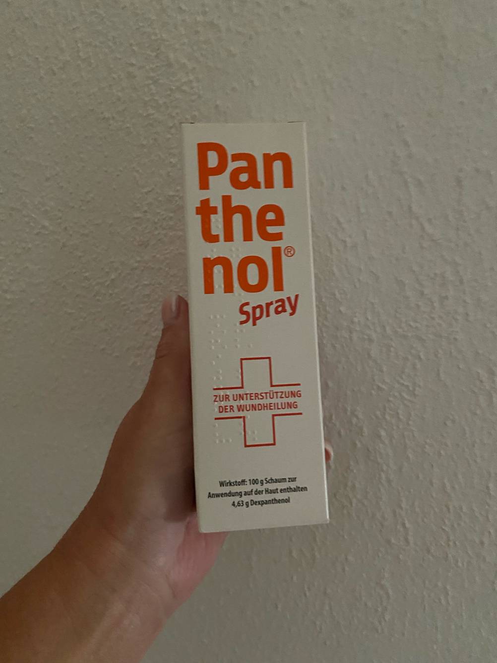 Das getestete Panthenol wird in der Hand vor einer weißen Wand gehalten.