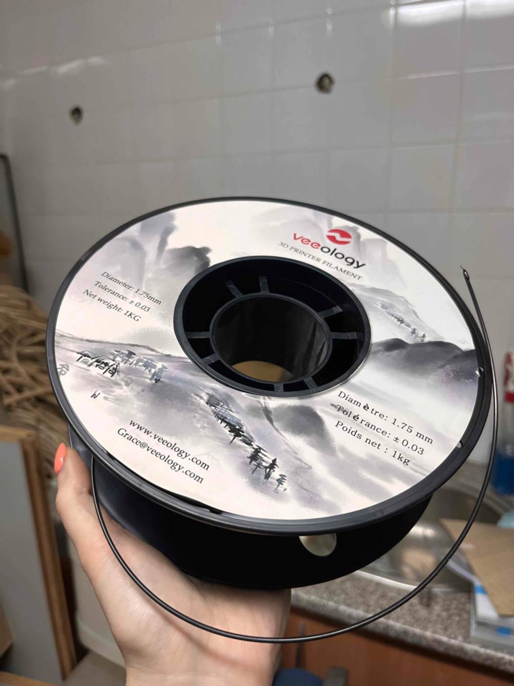 Eine Hand hält eine Rolle getestetes 3D-Drucker-Filament.