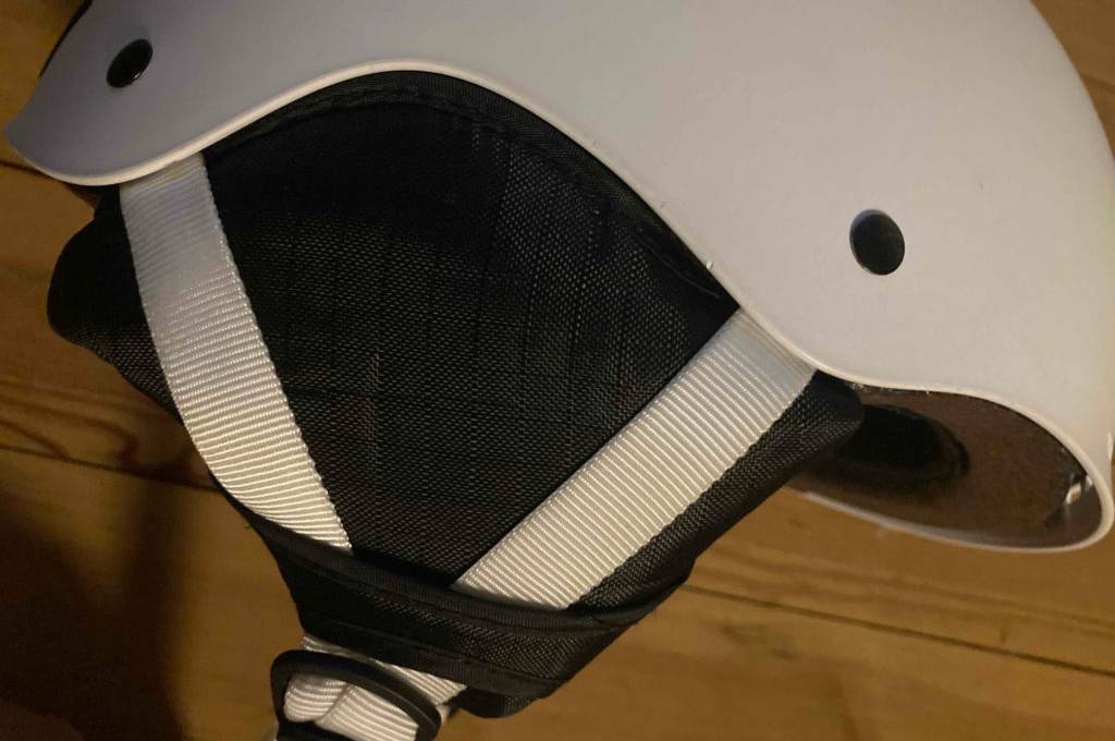 Snowboardhelm im Test: weißer Snowboardhelm mit Fokus auf die seitlichen Kinnbänder.