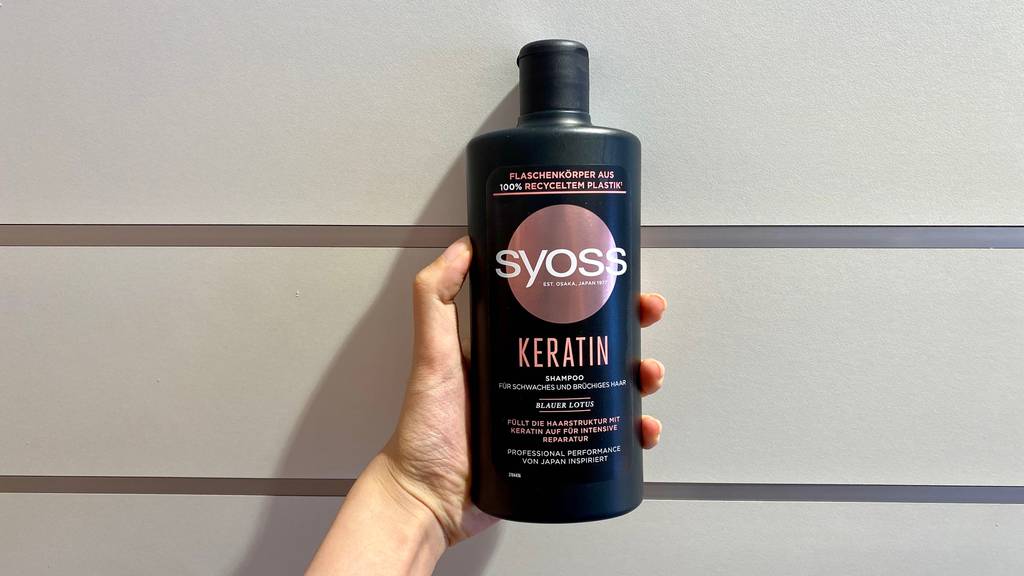 Keratin-Shampoo im Test: Syoss Shampoo in der Hand vor einer Wand.