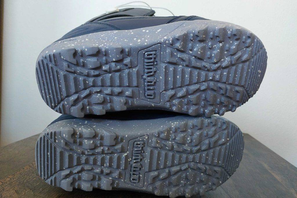 Snowboard-Boots getestet: Sohlen von Boots die auf einer Holzoberfläche liegen