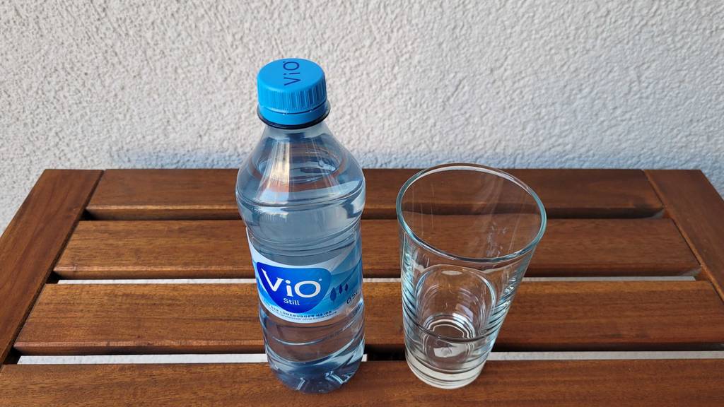 Stilles-Mineralwasser und leeres Glas daneben.