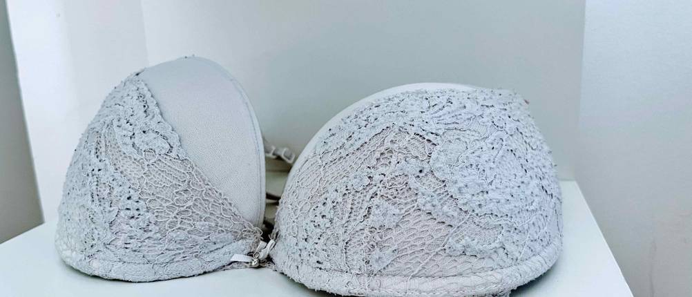 Dirndl-BH im Test: Ein Dirndl-BH mit Spitzenbesatz über Cups liegt in einem weißen Regal