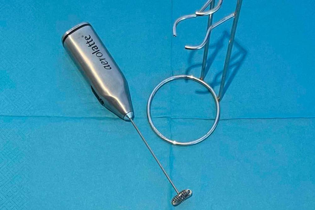 Ein getesteter Stab-Milchaufschäumer neben einem Ständer auf blauer Oberfläche