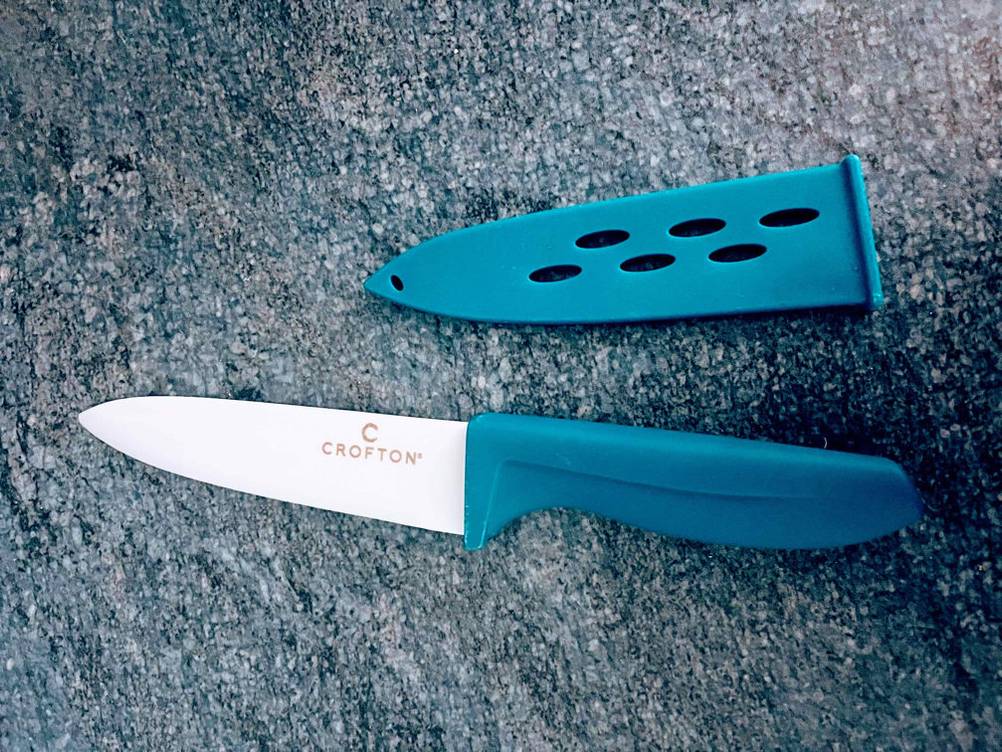 Keramikmesser getestet: Keramikmesser mit blauer Schutzkappe daneben liegend.