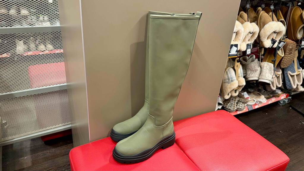 Getestet: Ein Paar Winter-Gummistiefel in der Farbe Grün stehen auf einem Sitzhocker in einem Geschäft.