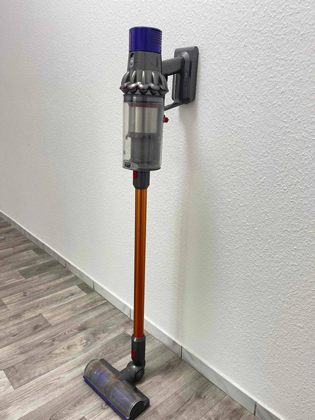 Der getestete Dyson-V10-Filter ist an einem Staubsauger befestigt, welcher an einer Wand lehnt.