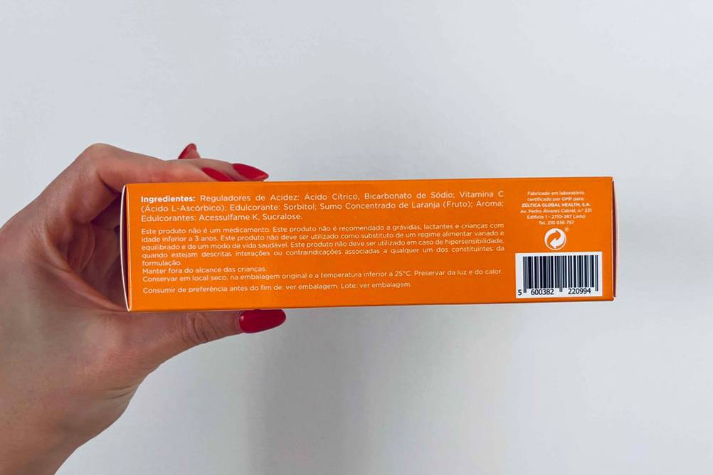 Vitamin-C im Test: Eine Hand hält die Rückseite mit den Inhaltsstoffen einer Packung Vitamin-C vor eine helle Wand