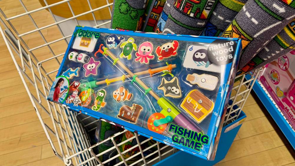 Das getestete Angelspiel, welches sich in einer transparenten Verpackung befindet, liegt in einem Korb, worin sich Teppiche befinden.