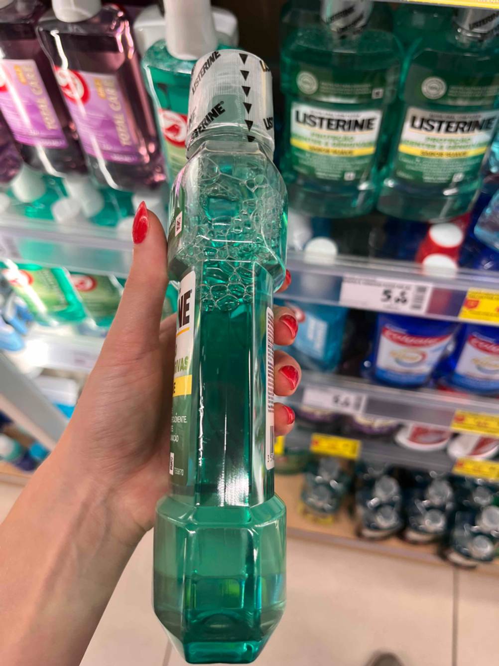 Eine getestete Listerine-Mundspülung wird mit der Seite der Flasche ersichtlich in der Hand gehalten.