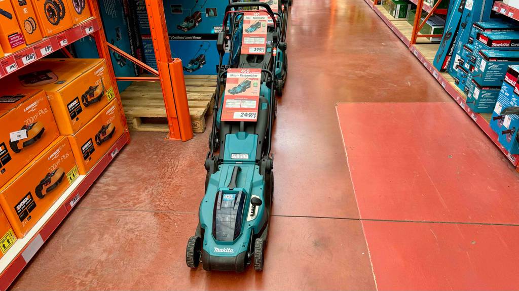 Makita-Akku-Rasenmäher-Test: mehrere Rasenmäher stehen hintereinander in einem Geschäft, mit den entsprechenden Preisschildern darauf.