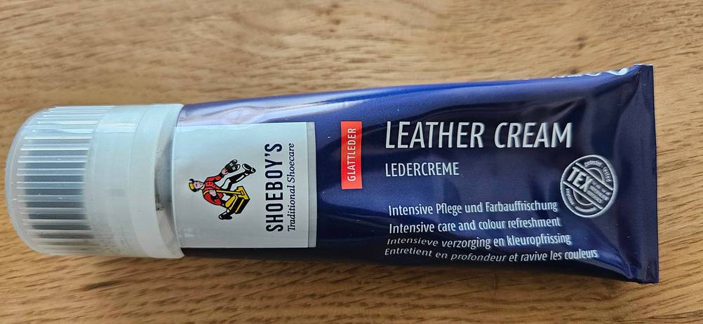 Eine Tube der getesteten Schuhcreme horizontal auf einer Holzfläche.