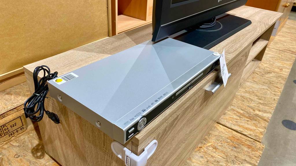 DVD-Player im Test: ein DVD-Player steht auf einem Sideboard mit zusammengebundenem Kabel.