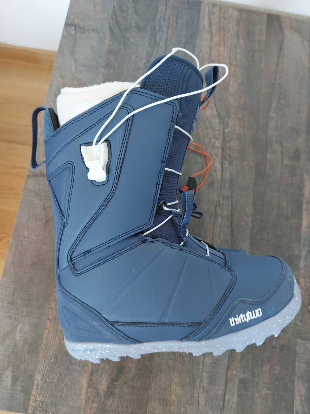Ein getesteter Snowboard-Boot auf der Seite liegend auf einer Holzfläche.