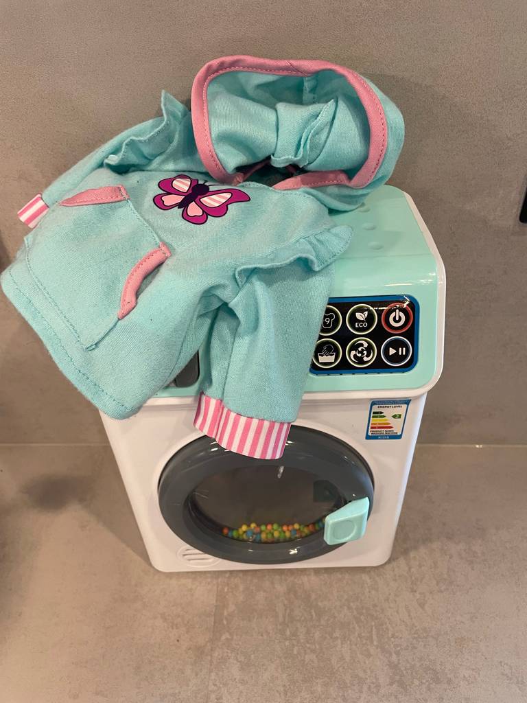 Getestete Kinderwaschmaschine mit Kleidung darauf.