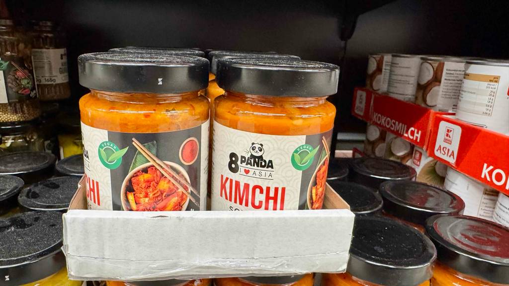 Mehrere Gläser mit getestetem Kimchi der Marke 8Panda stehen im Karton auf einem Verkaufsregal.
