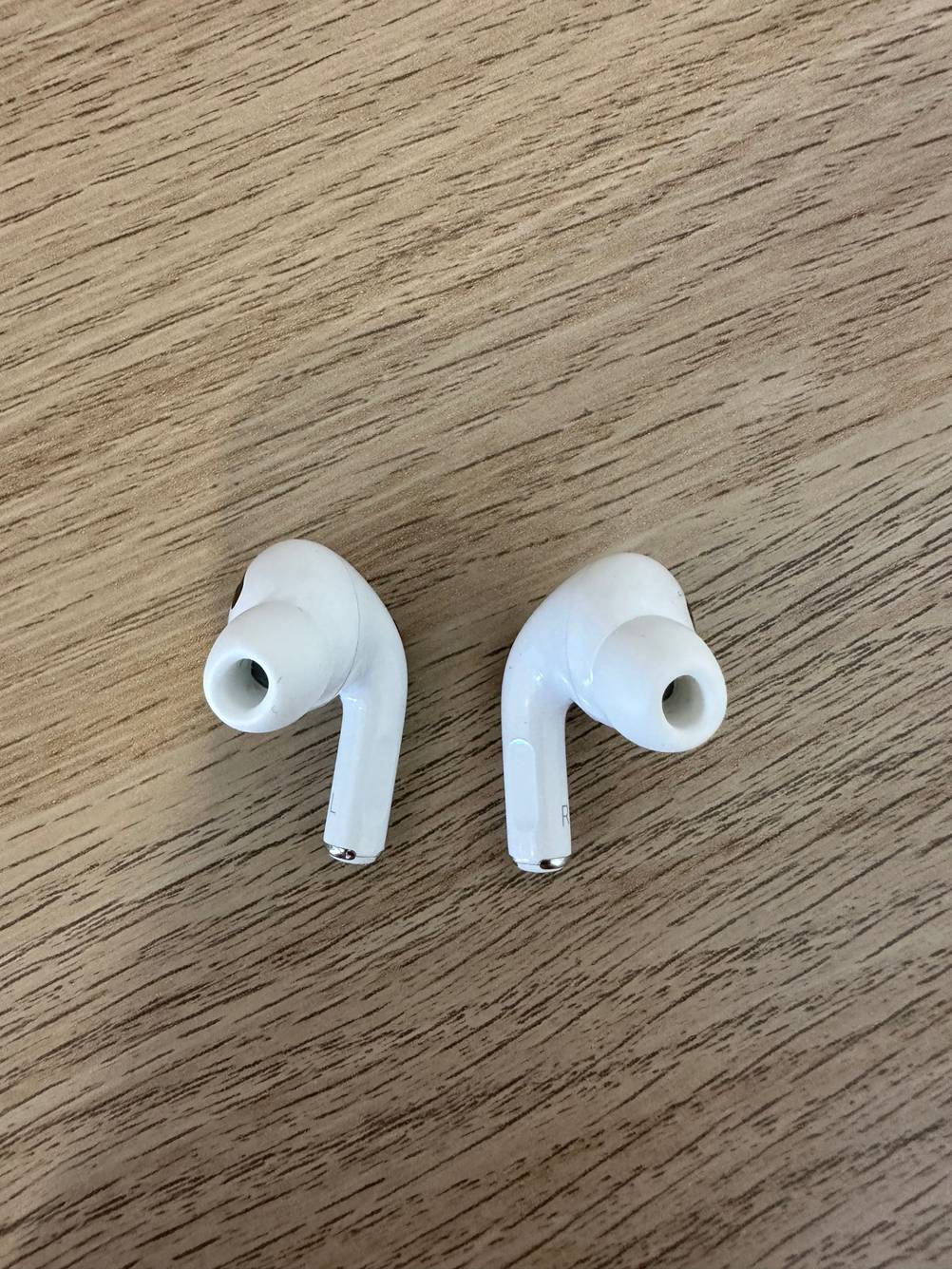 Zwei getestete True-Wireless-In-Ear-Kopfhörer liegen auf einer Holzfläche.