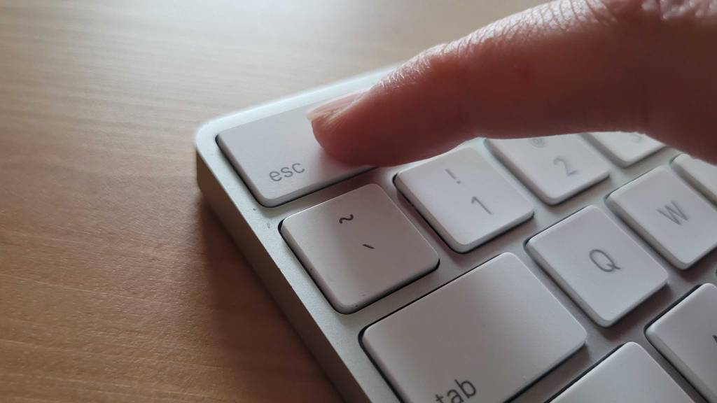Tastatur-Test: Finger drückt auf die Escape Taste einer weißen Tastatur.