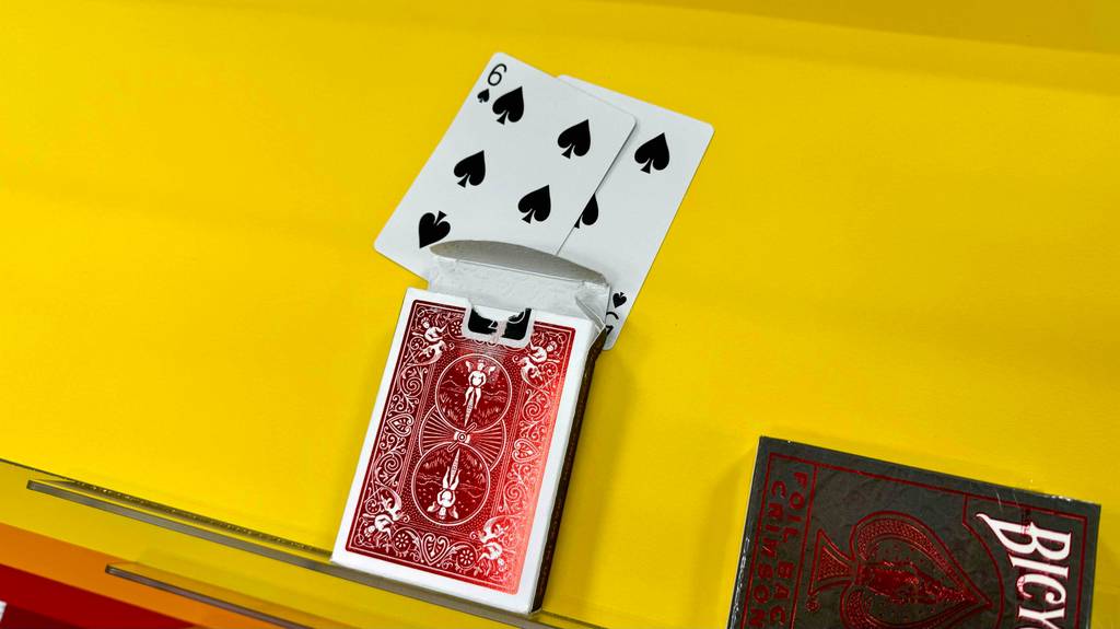 Eine getestete Packung Pokerkarten liegen auf einer gelben Fläche mit zwei Karten davor liegend.