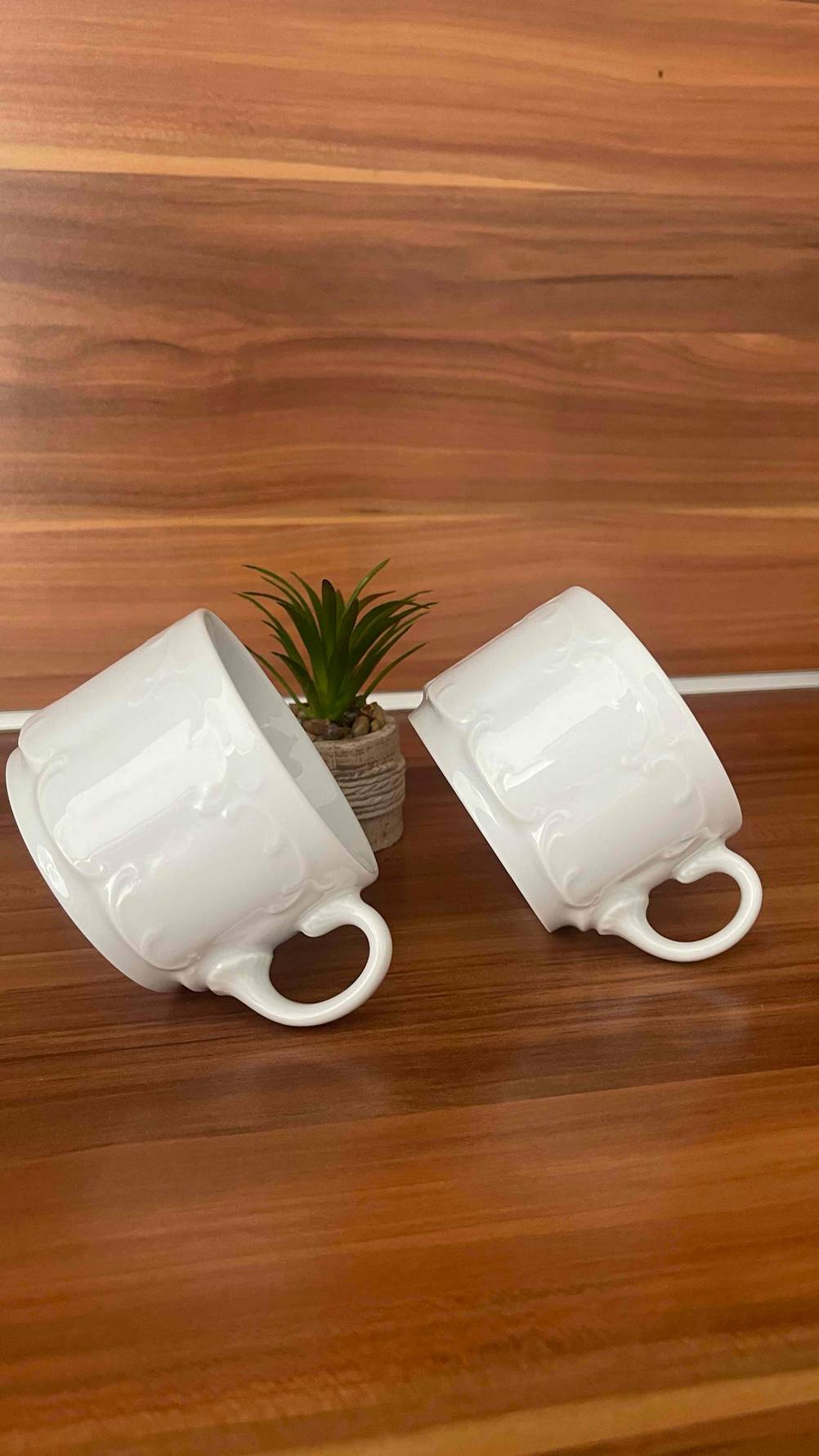Zwei getestete Cappuccino-Tassen sind auf einer Holzfläche schräg platziert.