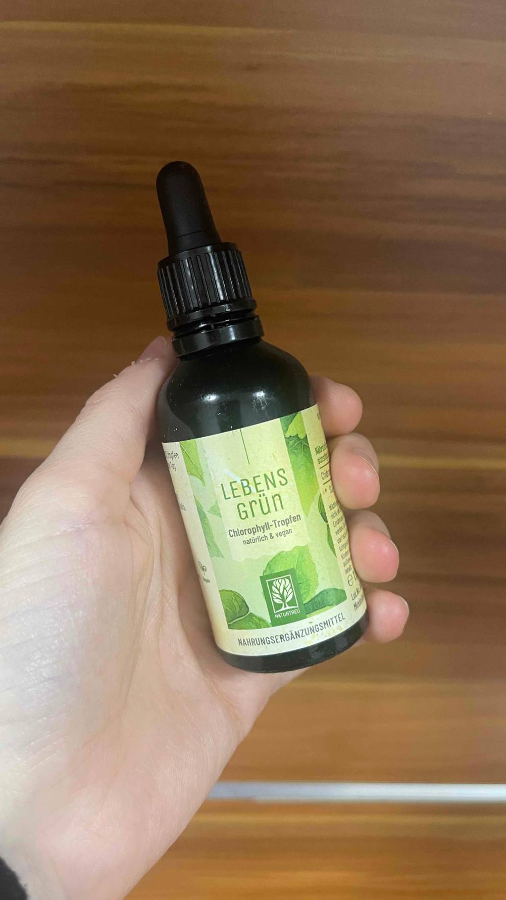 Die getesteten Chlorophyll-Tropfen, die sich in einem dunklen Fläschchen befinden, werden in der Hand gehalten.