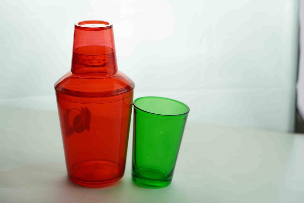Cocktail-Shaker getestet: Ein rottransparenter Shaker neben einem grünen Glas auf einer weißen Oberfläche