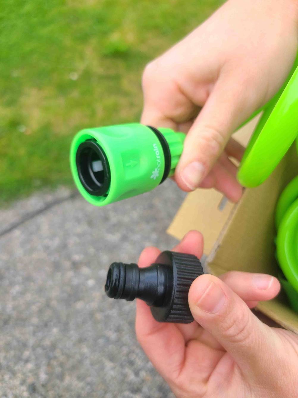Die Verbindungsstücke des getesteten Spiral-Gartenschlauchs werden in der Hand gehalten.