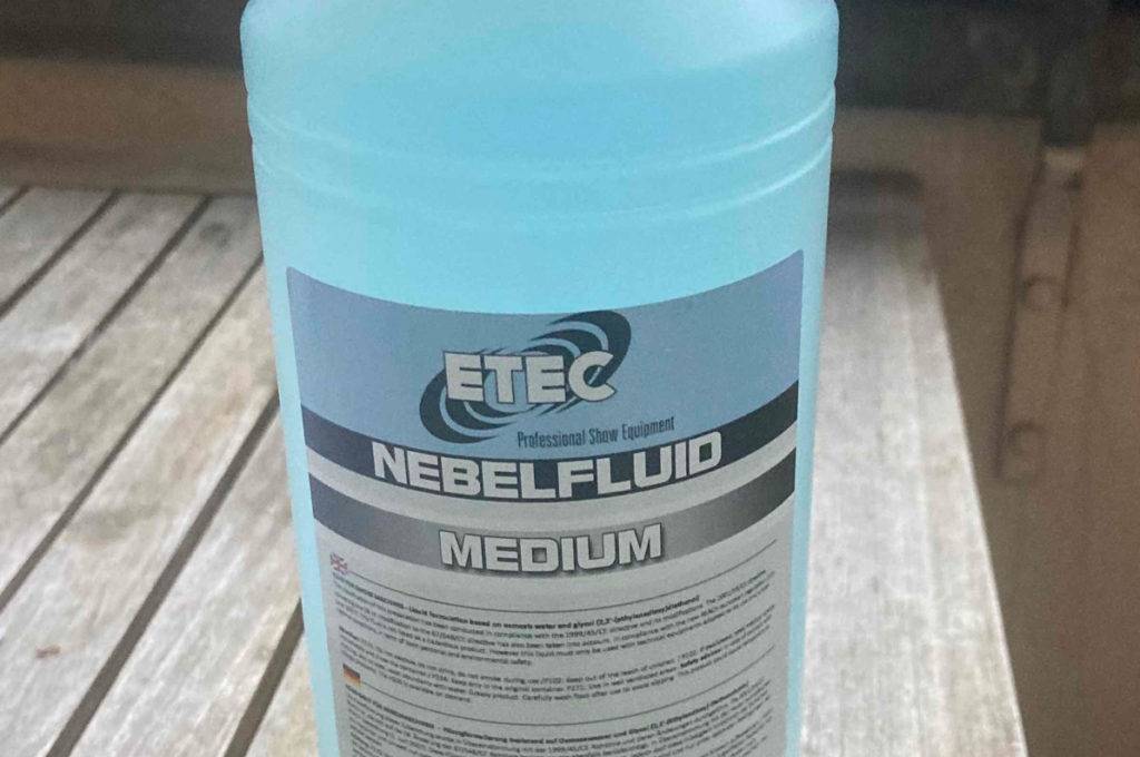 Eine Flasche getestetes Nebelfluid steht auf einem Holztisch.